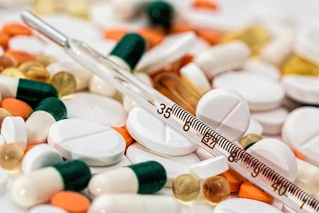 A close-up image of various pills and capsules in different colors and shapes scattered across a surface, with a thermometer displaying 35.6°C resting among them, symbolizing a windshield assessment for abundant healthcare resources.